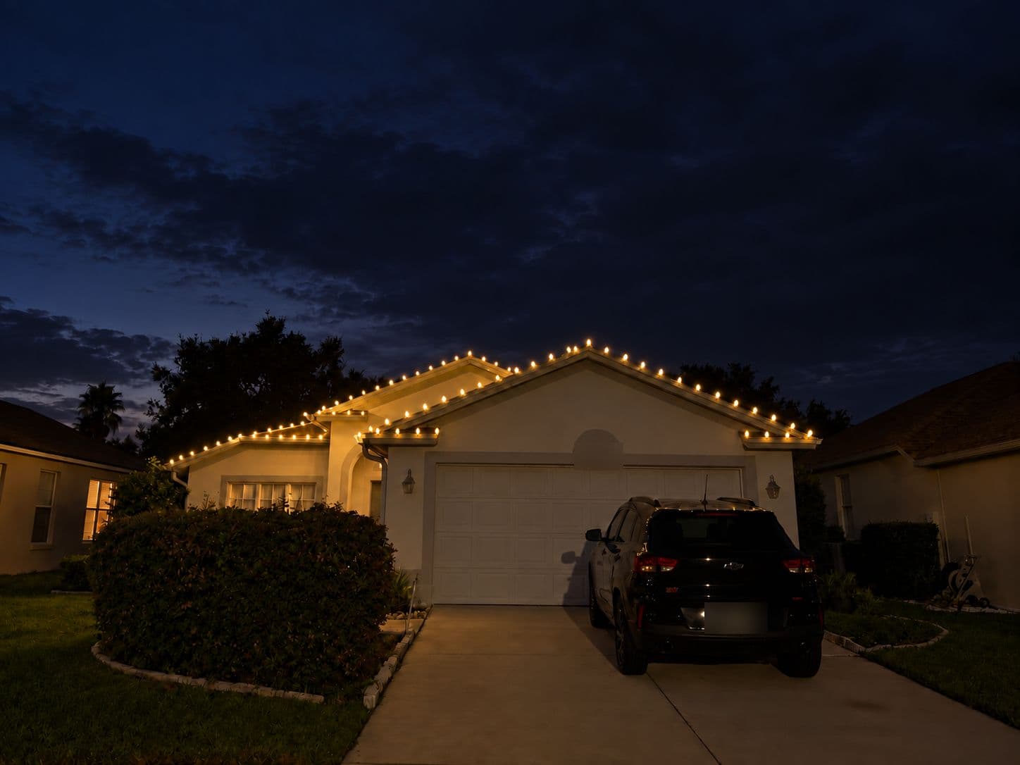 A home at dusk with warm white C9 lights along the garage gables and rooflines